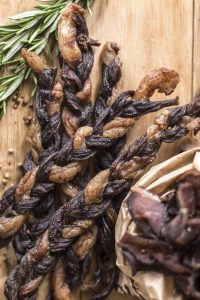 Amazing Biltong Koeksisters standing next to sliced biltong pieces in a bag